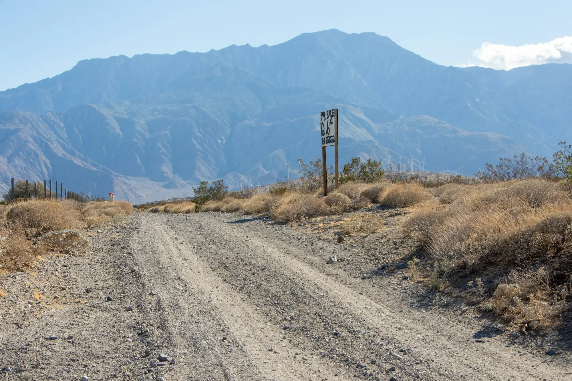 A long unsealed road running toward distant ranges, the kind of distance covered when a work vehicle is bought in another state