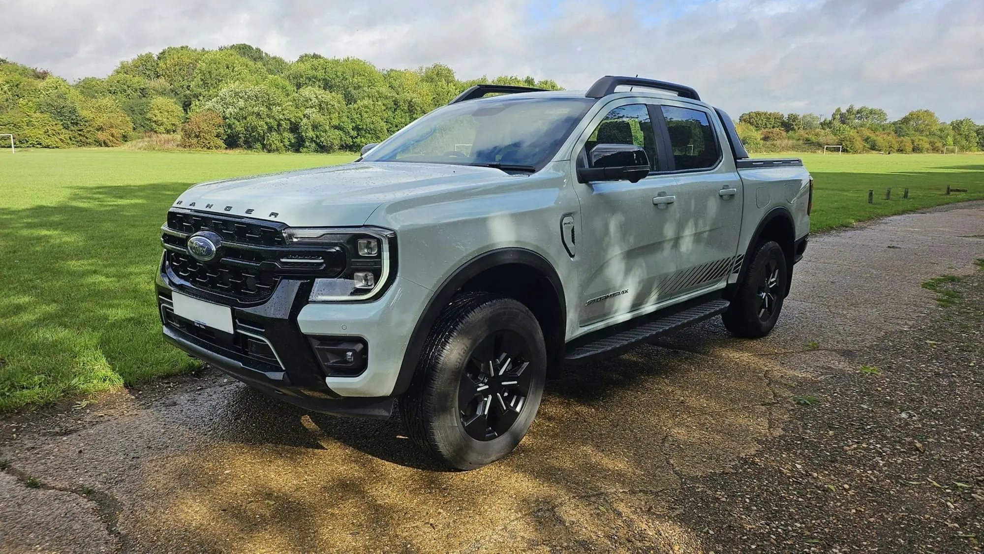 Light grey Ford Ranger Wildtrak dual-cab ute parked on a gravel road beside a park