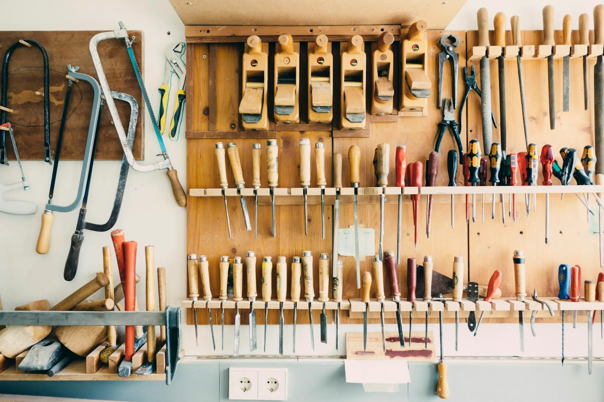 Wall-mounted rack of saws, planes, chisels and hand tools in a workshop — the kind of gear that eats into a work ute's payload before a trailer is even hitched